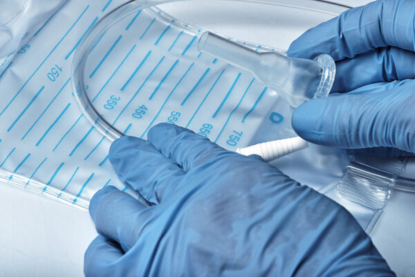 Hands in rubber gloves hold a catheter
